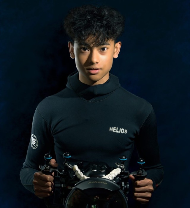 Pari in a wetsuit, holding his underwater camera housing